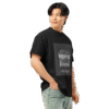 Right-front angled view of a black men’s box-fit t-shirt with a structured silhouette and classic crew neckline. Displayed against a neutral background, the shirt’s deep tone and clean lines reflect the bold, minimalist aesthetic of the “Good Kid Maad City” collection—channeling lyrical grit and urban style into wearable form.
